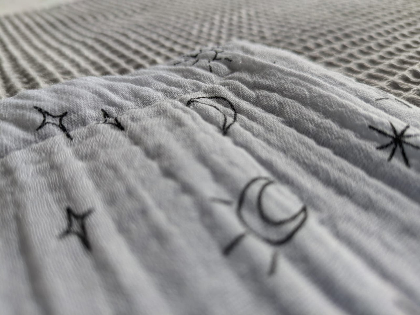 Plaid Sami gris y blanca  con estampados de sol, estrellas y lunas. - Suavidad al tacto